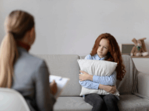 a young person sitting on a couch with a therapist